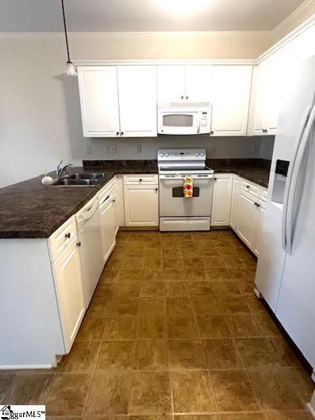 kitchen with white appliances, a sink, white cabinetry, dark countertops, and decorative light fixtures