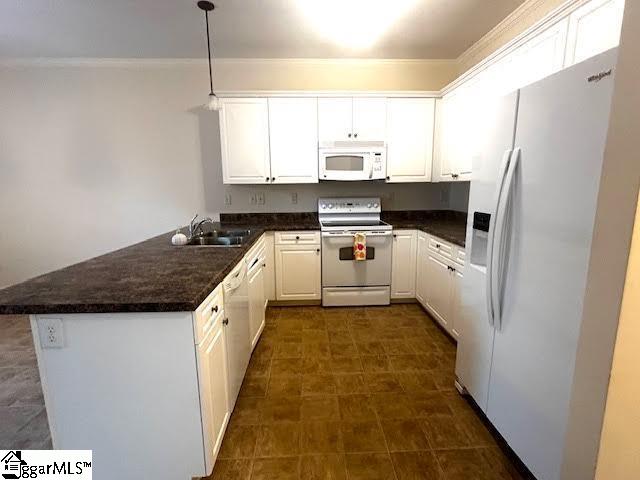 kitchen with dark countertops, white appliances, a peninsula, and white cabinets