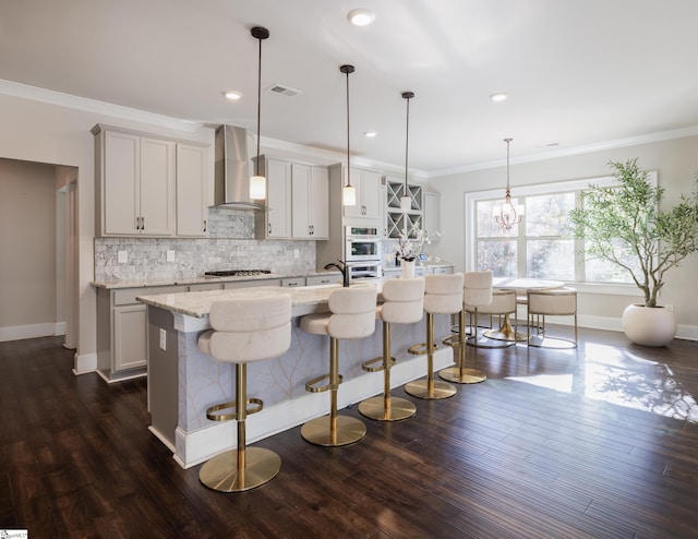 kitchen with stainless steel appliances, hanging light fixtures, wall chimney range hood, dark hardwood / wood-style floors, and a breakfast bar