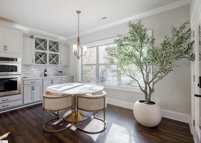 dining space with crown molding, a chandelier, and dark hardwood / wood-style floors