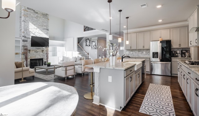 kitchen with hanging light fixtures, stainless steel appliances, dark hardwood / wood-style flooring, a breakfast bar area, and a kitchen island with sink