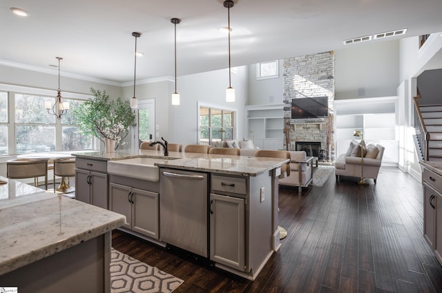 kitchen featuring hanging light fixtures, light stone counters, stainless steel dishwasher, gray cabinets, and a fireplace