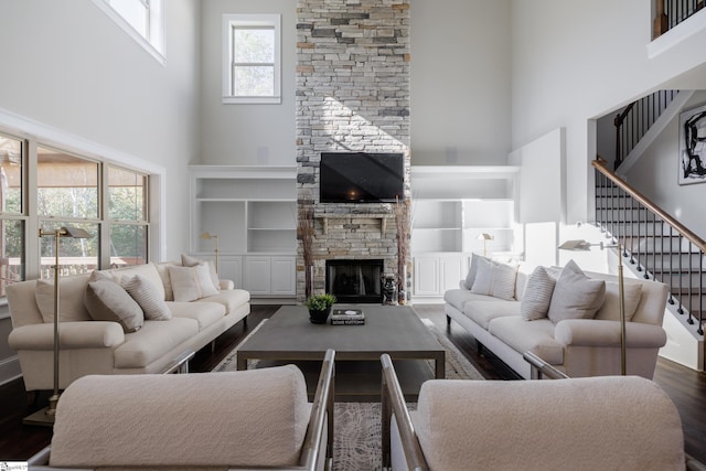 living room with dark hardwood / wood-style floors, a stone fireplace, and a high ceiling