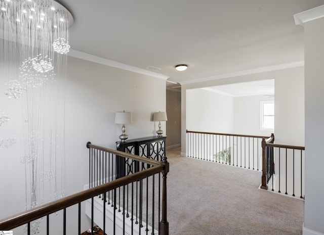 hall featuring carpet flooring, ornamental molding, and a notable chandelier