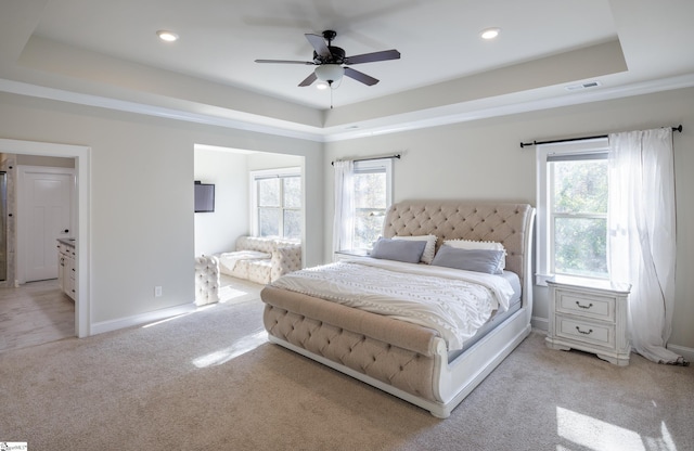 bedroom with a raised ceiling, ceiling fan, and light carpet