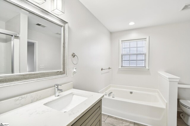 bathroom with tile patterned flooring, vanity, toilet, and a bath