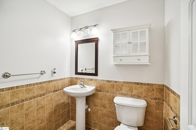 bathroom featuring toilet and tile walls