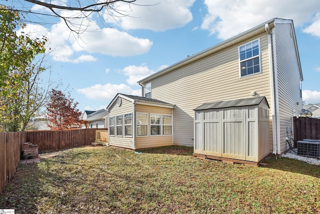 back of house with a lawn, central AC, and a storage unit