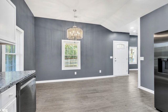 unfurnished dining area featuring an inviting chandelier, dark wood-type flooring, and vaulted ceiling