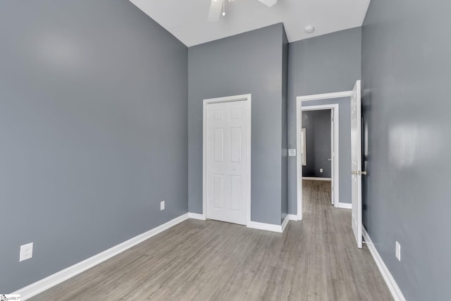 unfurnished bedroom featuring ceiling fan, a high ceiling, and light wood-type flooring