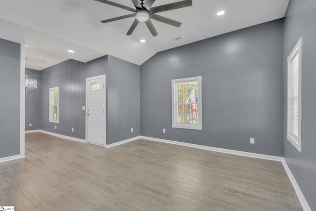 unfurnished room with light hardwood / wood-style flooring, ceiling fan with notable chandelier, and vaulted ceiling