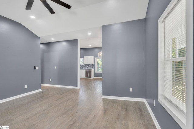 empty room with hardwood / wood-style flooring, ceiling fan, lofted ceiling, and a wealth of natural light