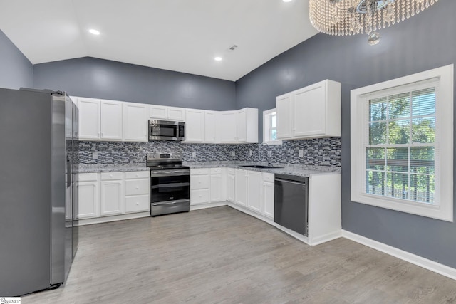 kitchen with tasteful backsplash, stainless steel appliances, sink, an inviting chandelier, and white cabinetry