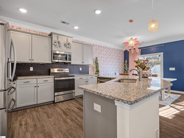 kitchen with pendant lighting, crown molding, sink, and appliances with stainless steel finishes