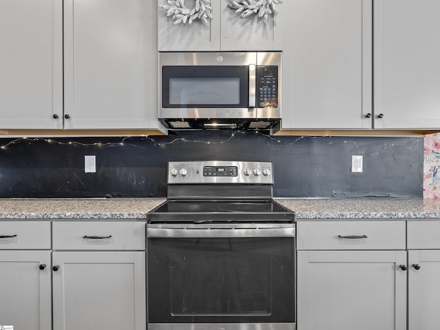 kitchen featuring backsplash, light stone counters, white cabinets, and appliances with stainless steel finishes