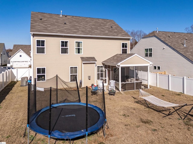 rear view of property with a trampoline, a lawn, and a sunroom