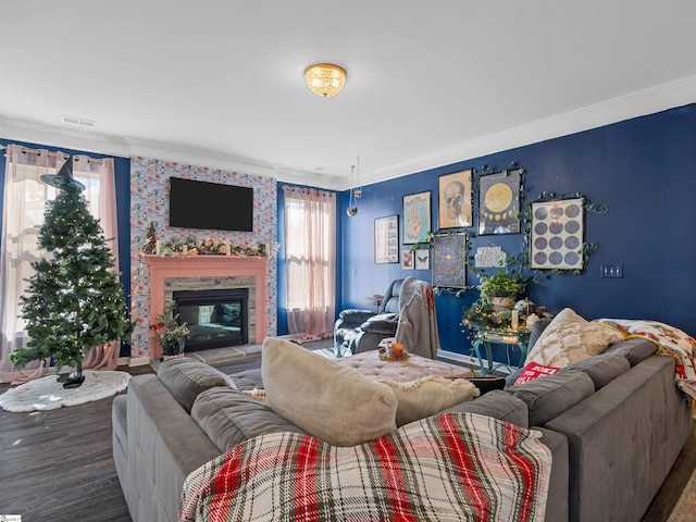 living room featuring hardwood / wood-style floors, a stone fireplace, and ornamental molding