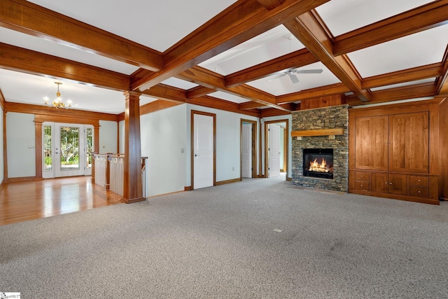 unfurnished living room with a stone fireplace, ornate columns, and light carpet