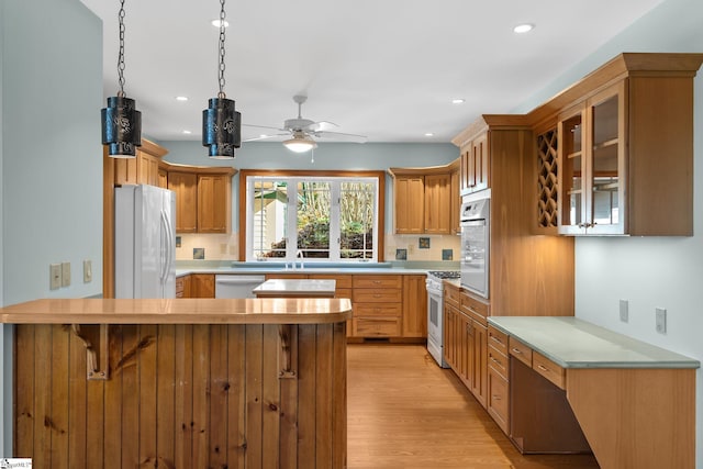 kitchen featuring a kitchen breakfast bar, ceiling fan, light wood-type flooring, appliances with stainless steel finishes, and tasteful backsplash