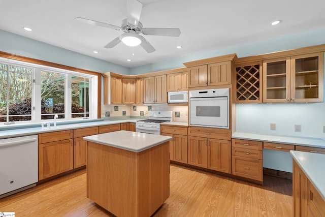 kitchen featuring white appliances, ceiling fan, sink, light hardwood / wood-style flooring, and a center island