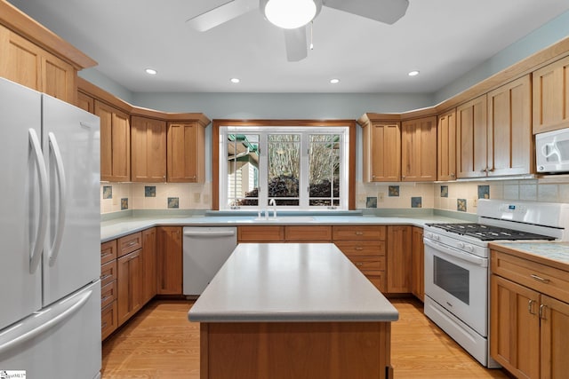 kitchen featuring decorative backsplash, a center island, white appliances, and light hardwood / wood-style floors