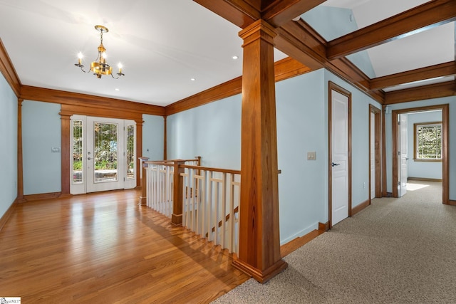 hallway with beam ceiling, ornate columns, light hardwood / wood-style floors, and an inviting chandelier