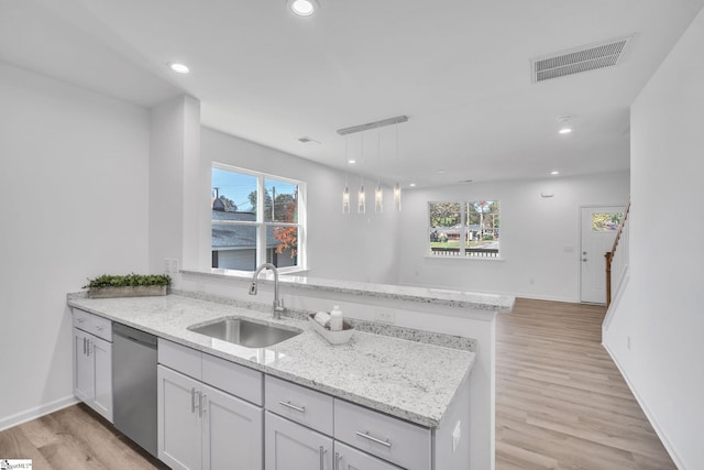 kitchen with dishwasher, kitchen peninsula, light hardwood / wood-style flooring, and sink