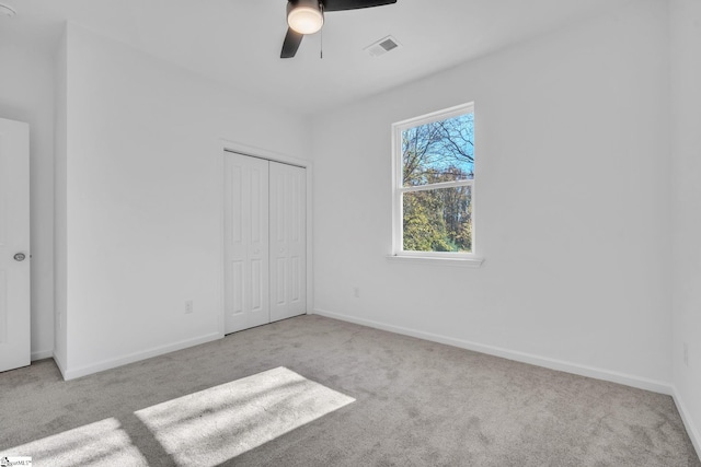 unfurnished bedroom with ceiling fan, light carpet, and a closet