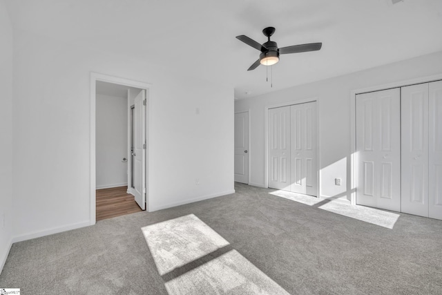 unfurnished bedroom featuring two closets, light colored carpet, and ceiling fan