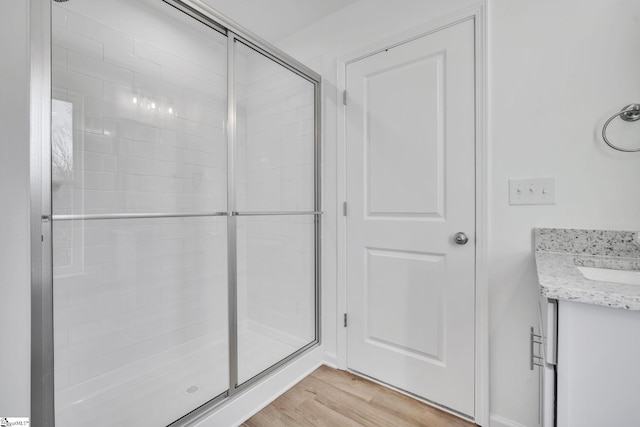 bathroom with hardwood / wood-style floors, vanity, and a shower with door