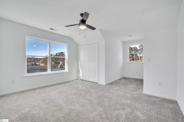 unfurnished bedroom featuring ceiling fan, lofted ceiling, light carpet, and a closet