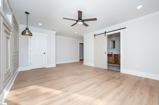 interior space featuring light wood-type flooring, a barn door, and crown molding