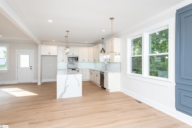 kitchen with white cabinets, appliances with stainless steel finishes, light stone counters, and a wealth of natural light