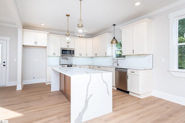 kitchen featuring light stone countertops, stainless steel appliances, pendant lighting, a center island, and white cabinetry