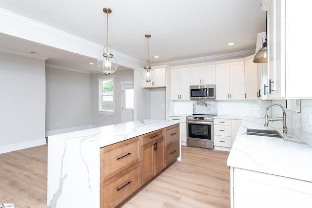 kitchen featuring light stone counters, stainless steel appliances, decorative light fixtures, white cabinets, and a kitchen island