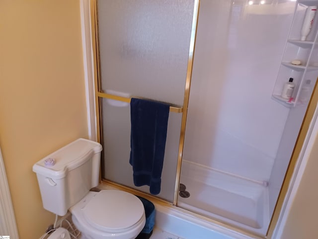 bathroom featuring toilet and a shower with shower door