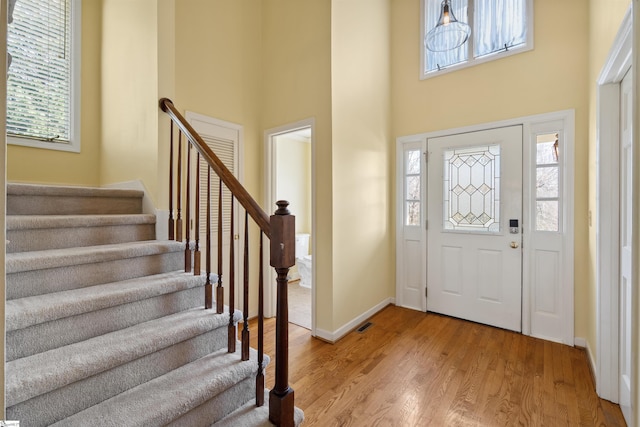 entrance foyer with stairway, a high ceiling, baseboards, and light wood-type flooring