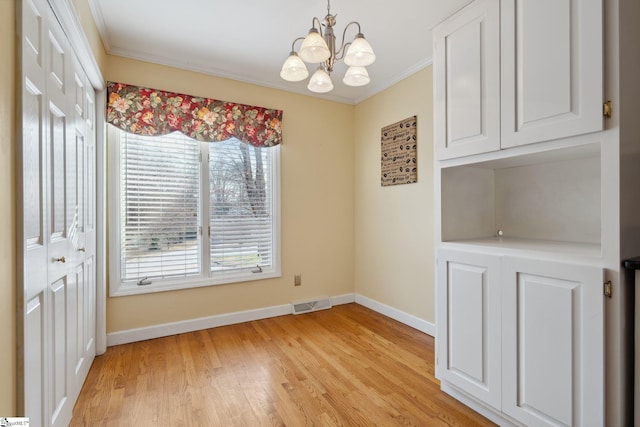 unfurnished dining area with visible vents, a notable chandelier, light wood-style floors, crown molding, and baseboards