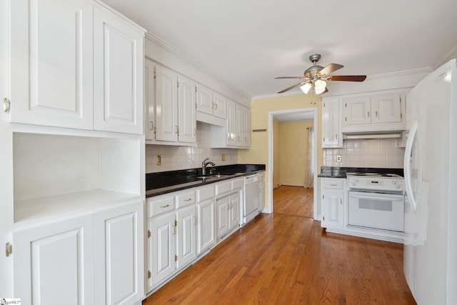 kitchen with dark countertops, light wood finished floors, ornamental molding, white appliances, and white cabinetry