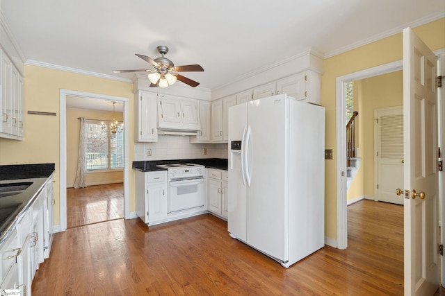 kitchen featuring white appliances, dark countertops, wood finished floors, and white cabinetry