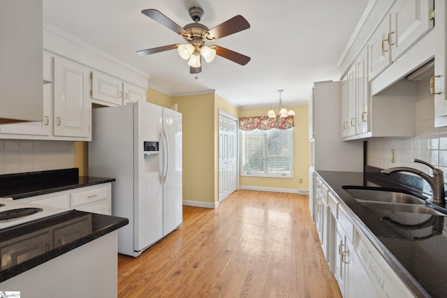 kitchen with white appliances, light wood finished floors, ornamental molding, a sink, and dark countertops