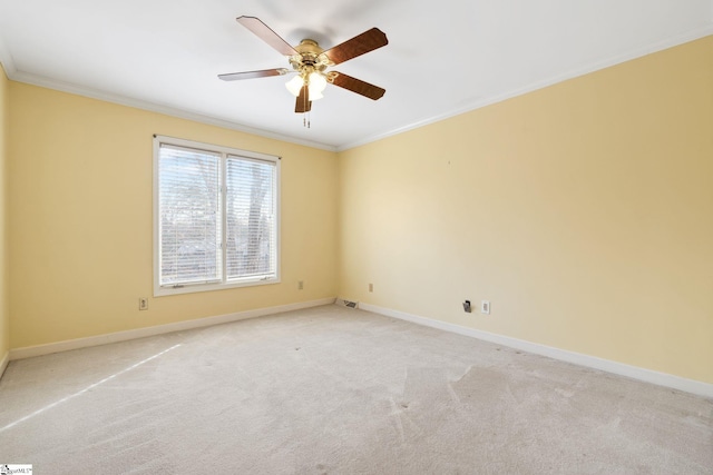 empty room featuring ceiling fan, crown molding, baseboards, and light carpet