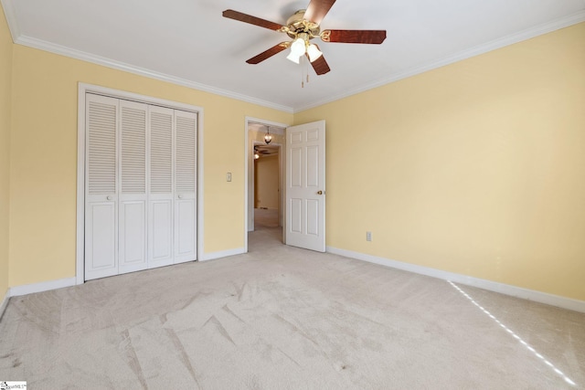 unfurnished bedroom featuring ceiling fan, baseboards, carpet, ornamental molding, and a closet