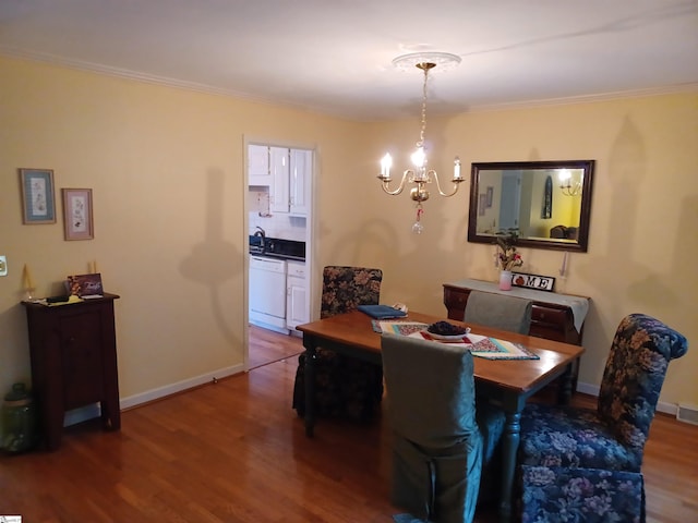 dining area with a notable chandelier, crown molding, baseboards, and wood finished floors