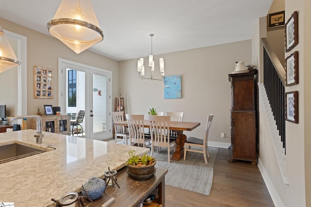 dining room featuring hardwood / wood-style flooring, an inviting chandelier, sink, and french doors