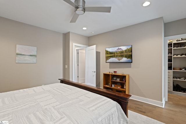 bedroom with hardwood / wood-style flooring, ceiling fan, a walk in closet, and a closet