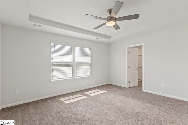 carpeted spare room featuring ceiling fan and a raised ceiling