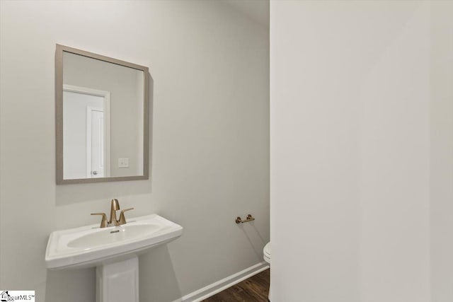 bathroom featuring toilet, wood-type flooring, and sink