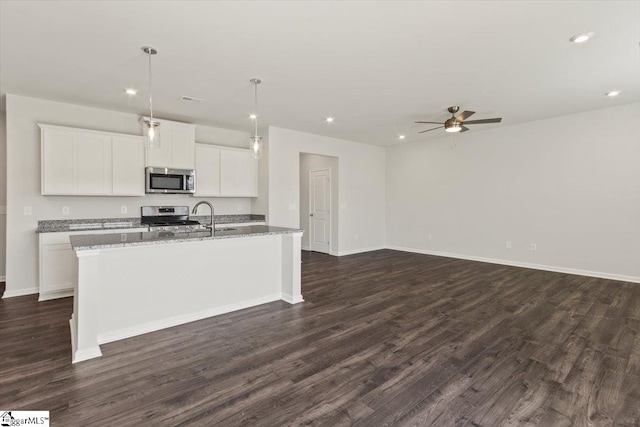 kitchen featuring white cabinets, hanging light fixtures, an island with sink, appliances with stainless steel finishes, and dark hardwood / wood-style flooring