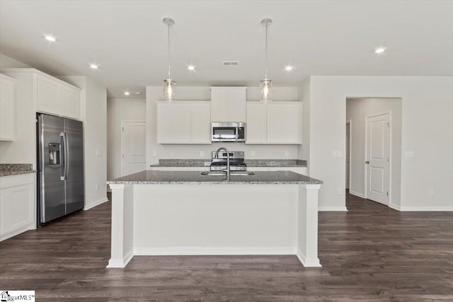 kitchen featuring hanging light fixtures, dark hardwood / wood-style flooring, stainless steel appliances, and a kitchen island with sink